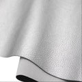 A close-up of a light gray pebbled faux leather or vinyl material sheet, partially rolled over to show its texture and underside on a white background.