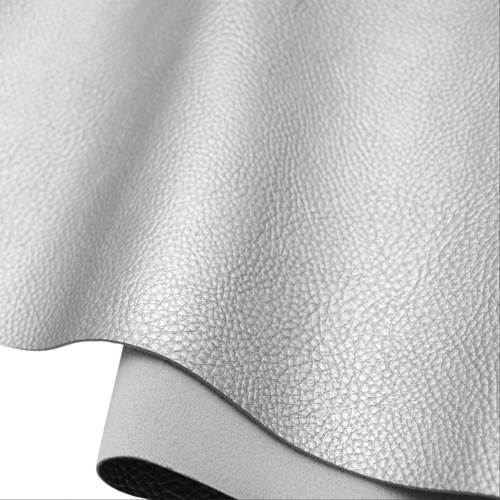 A close-up of a light gray pebbled faux leather or vinyl material sheet, partially rolled over to show its texture and underside on a white background.